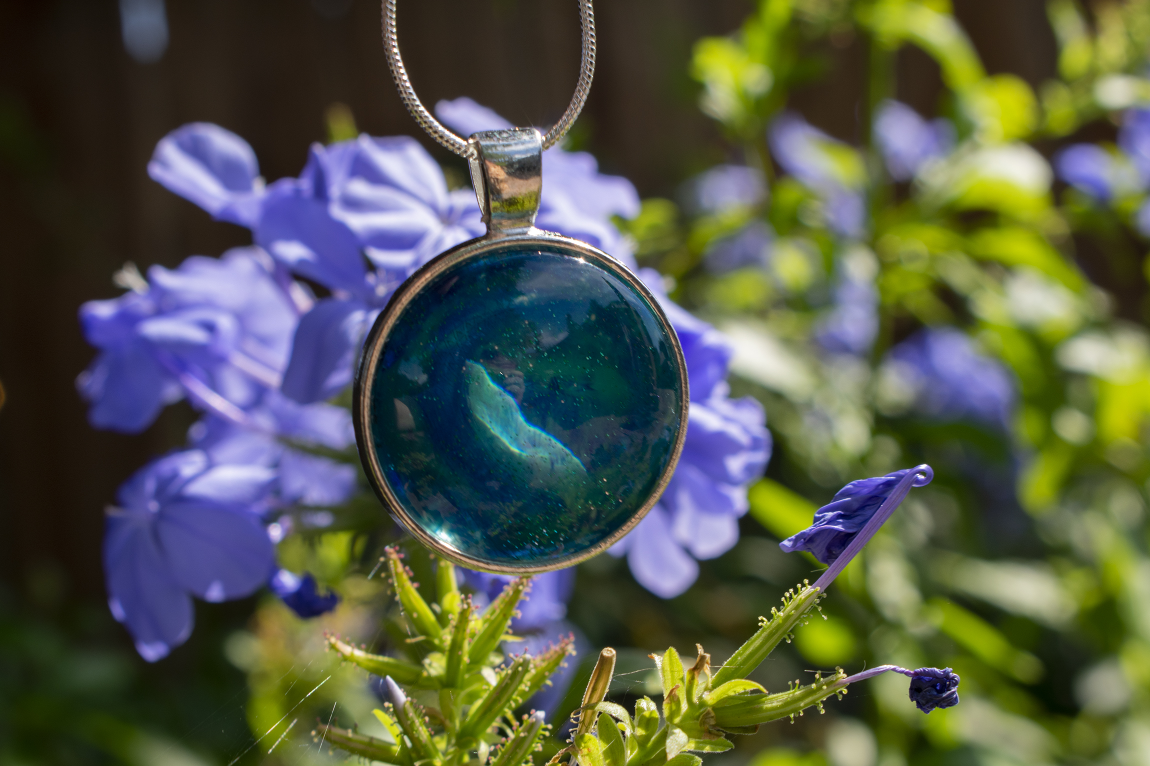 A blue circle necklace in front of flowers